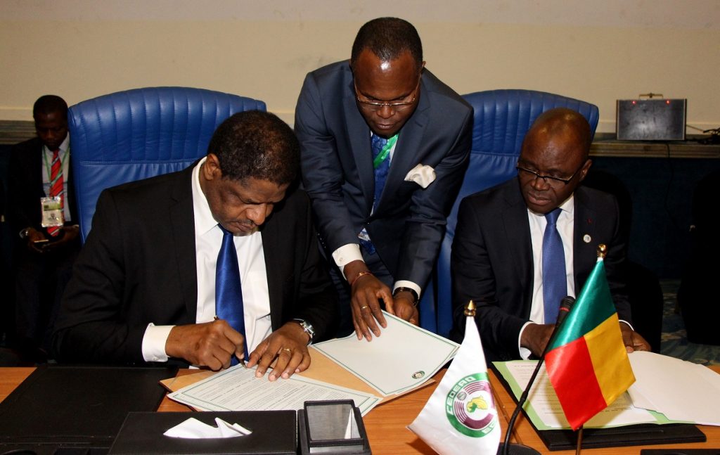 H.E. Marcel de Souza, President of the ECOWAS Commission, left, assisted by Mr. Abel Agbebleo, Director of Cabinet, ECOWAS, and H.E. Aurélien Agbénonci, Honourable Minister of Foreign Affairs, Republic of Benin, right, signing the Agreement on Centre Maritime Multinationale de Coordination de La Zone E in Abuja, 17th December 2016.